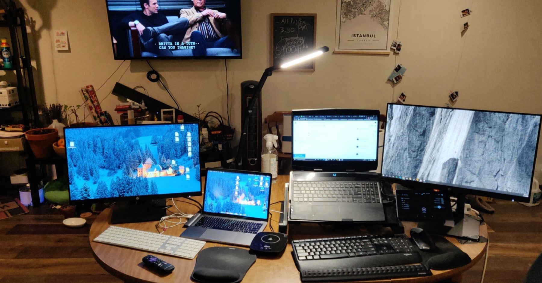 A home desk with four monitors, a laptop and two keyboards