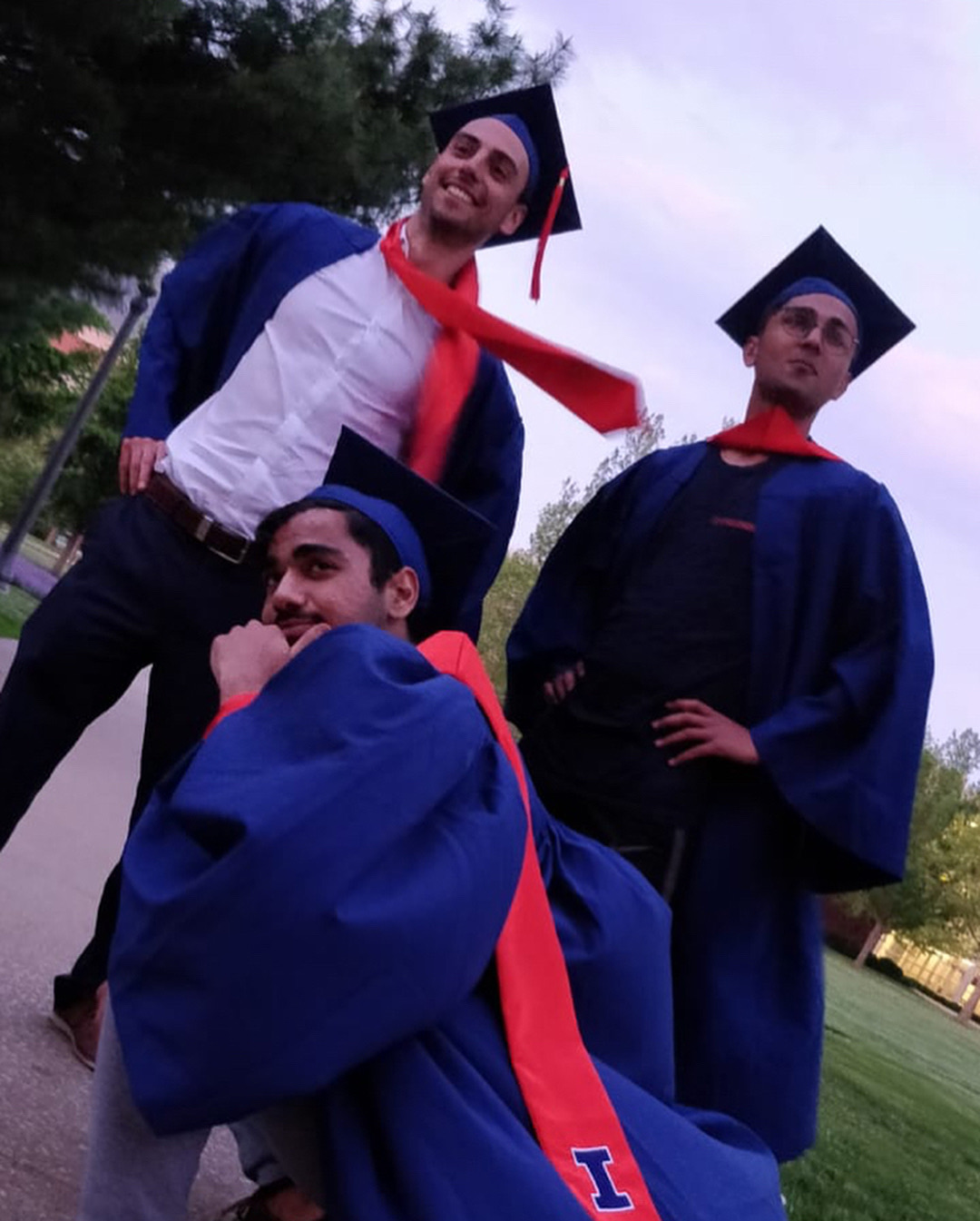 Volga and two friends in blue Illinois graduation gowns and caps