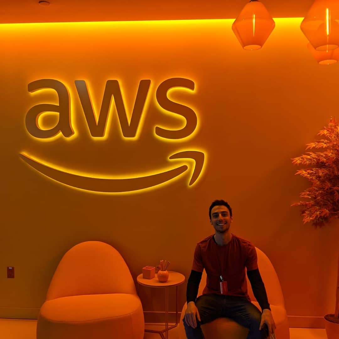 Volga sitting in an orange-lit lounge under a glowing AWS sign